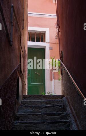 Porta verde in un vicolo colorato e stretto in un tradizionale villaggio italiano. Foto Stock