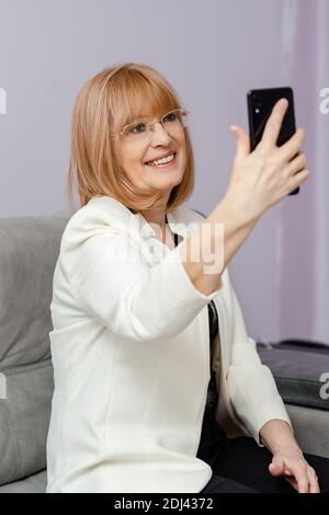 Donna anziana positiva che assume selfie e sorride. Concetto di pensionamento Foto Stock