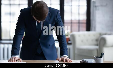 Primo piano frustrato uomo d'affari in piedi alla scrivania con testa giù Foto Stock