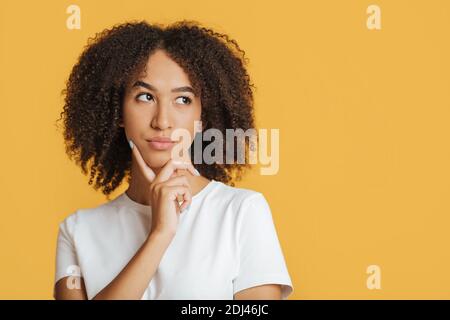 Scelta, proposta o decisione difficili. La giovane donna afroamericana pensiva preme il dito sul mento Foto Stock