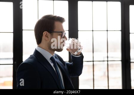 Vista laterale uomo d'affari sicuro indossare occhiali bere acqua minerale pura Foto Stock