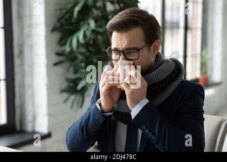 Primo piano impiegato malato che indossa sciarpa calda soffia naso che corre Foto Stock