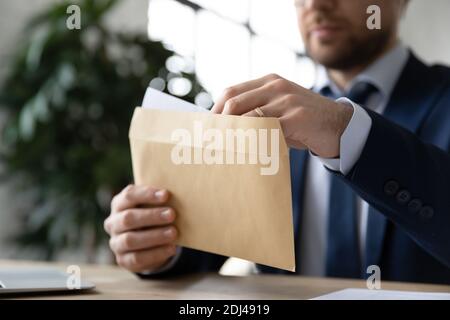 Primo piano uomo d'affari apertura busta di carta con lettera in ufficio Foto Stock