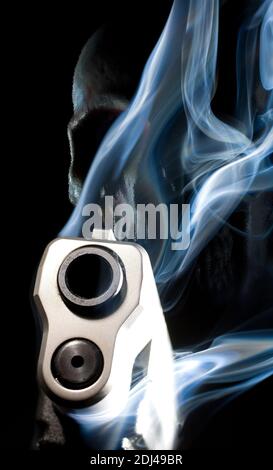 Rendering 3D di una pistola fantasma con fumo che sale da il barile e il cranio dietro su uno sfondo nero Foto Stock