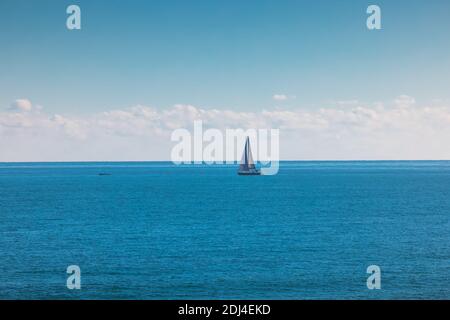 Mare e vela barca a vento. Barca a vela su onde blu e cielo soleggiato Foto Stock