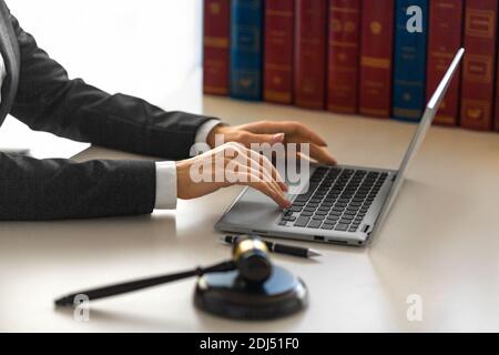Le mani femminili con la gavella di un giudice davanti a un monitor laptop. Ufficio legale. Foto Stock