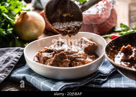 Carne di manzo cotta per uno stufato di carne con salsa versato sopra di esso un mestolo. Foto Stock