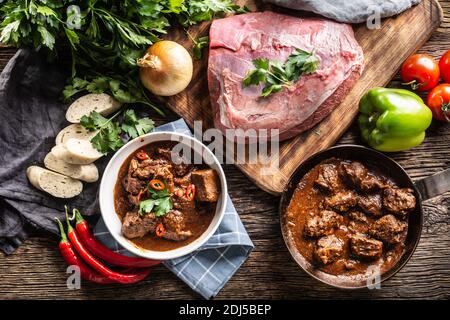 Vista dall'alto della festa del gulasch con pasto servito sui piatti in una ciotola, ingredienti e lati. Foto Stock