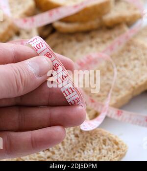 Contro un eccessivo aumento di peso a casa, pane di crusca, fette di pane di crusca e un metro a nastro, Foto Stock