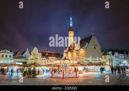 Tallinn, Estonia. Night Stars Sky sopra il tradizionale mercato di Natale e Carousel sulla Piazza del Municipio. Albero di Natale. Famoso punto di riferimento. Starry alterato Foto Stock