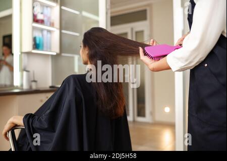 Parrucchiere pettina i capelli della donna, parrucchiere Foto Stock