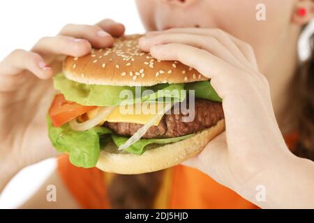 primo piano giovane ragazza che mangia un delizioso hamburger o sheeseburger con entrambe le mani da vicino. Concetto di fast food fotografato su sfondo bianco Foto Stock