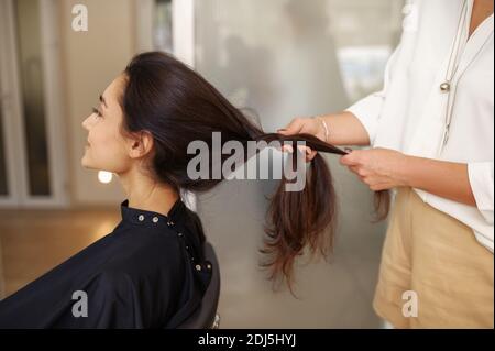 Il parrucchiere femminile pettina i capelli della donna, il parrucchiere Foto Stock