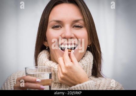 Giovane bella donna sorridente che prende la pillola dell'olio di pesce. Assunzione di capsule con omega 3 o vitamina D3. Integratori di vitamina D.