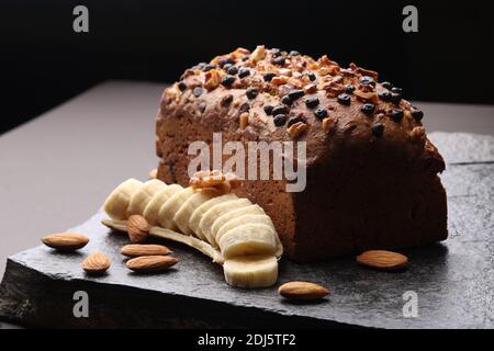 Pane di banana su fondo di pietra scura. Con mandorle e noce Foto Stock