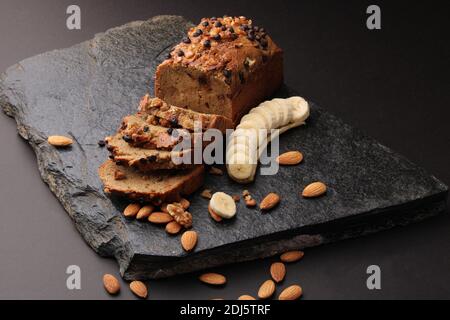 Pane di banana su fondo di pietra scura. Con mandorle e noce Foto Stock