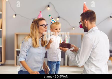 Felice madre e padre che si congratulano con il figlio piccolo con il compleanno con torta Foto Stock