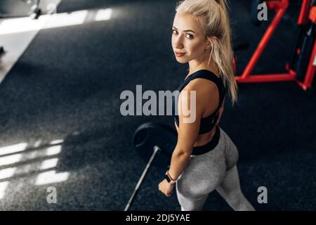 Donna fitness forte, in abbigliamento sportivo, si allena con pesi pesanti in palestra, Sportswoman solleva il barbell in palestra. Foto Stock