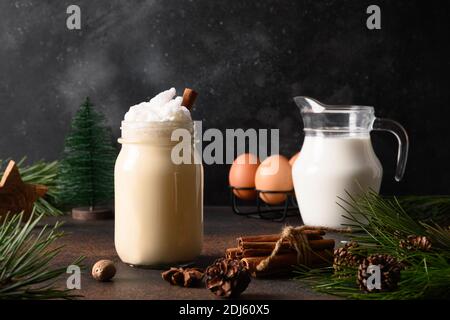 Eggnog di Natale in vasetto di muratore con ingredienti su sfondo marrone scuro. Primo piano. Foto Stock