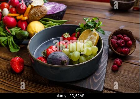 Frutta e bacche in piastra su sfondo di legno Foto Stock