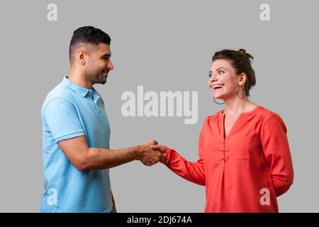 Piacere di conoscerti! Ritratto di felice coppia giovane in abbigliamento casual in piedi, sorridente ad ogni altro e stringono le mani, di incontro amichevole o un conoscente. i Foto Stock