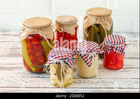 Varietà di sottaceti marinati che conservano i vasi. Pomodori fatti in casa, cetrioli, aglio, zenzero e sottaceti di rafano. Cibo fermentato Foto Stock