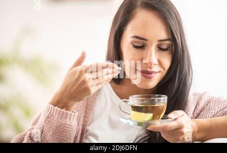 Una donna dall'aspetto gradevole gode dell'odore di un tè appena preparato. Foto Stock