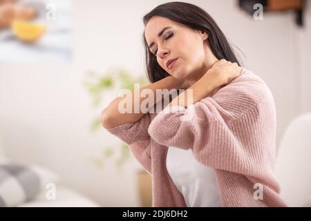 Collo rigido di una donna come lei si distingue da un divano a casa. Foto Stock