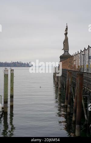 Decorazione di Natale sul molo o porto in città con scultura chiamata Imperia sullo sfondo e pali di ormeggio in acqua del lago di Costanza. Foto Stock