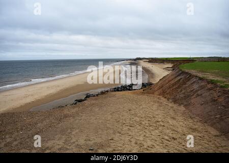 Una rampa di sabbia scende a Happisburgh Beach, accanto alle scogliere sul mare che mostrano l'erosione costale lungo la costa di Norfolk in Inghilterra. Foto Stock