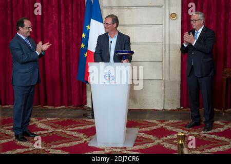 (L-R) il presidente francese Francois Hollande presenta il ciclista francese Bernard Hinault in pensione con un vaso Sevres come tributo alla sua carriera come presidente della Commissione europea Jean-Claude Juncker guarda al Palazzo Elysee a Parigi, in Francia, il 24 luglio 2016. Foto di Gilles Rolle/Pool/ABACAPRESS.COM Foto Stock