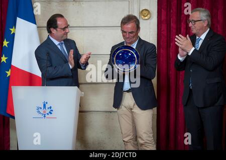(L-R) il presidente francese Francois Hollande presenta il ciclista francese Bernard Hinault in pensione con un vaso Sevres come tributo alla sua carriera come presidente della Commissione europea Jean-Claude Juncker guarda al Palazzo Elysee a Parigi, in Francia, il 24 luglio 2016. Foto di Gilles Rolle/Pool/ABACAPRESS.COM Foto Stock