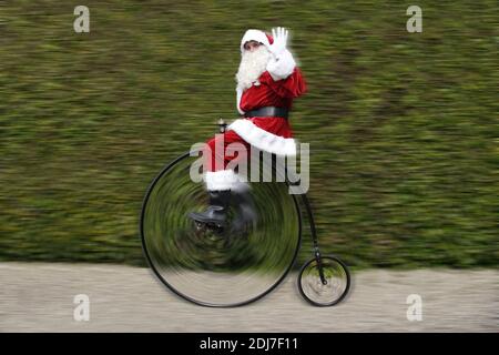 Padre Natale a cavallo di una bicicletta Penny Farthing e ondeggiamento Foto Stock