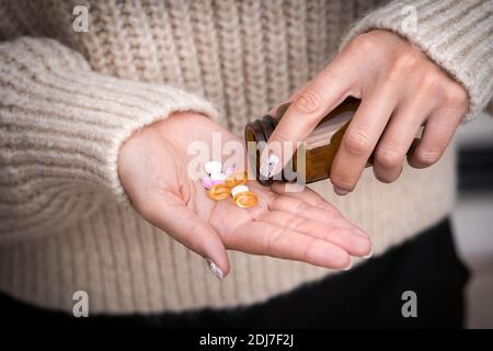 Primo piano sulle mani della donna che prendono vitamine, minerali e supplementi dal vaso. Foto Stock