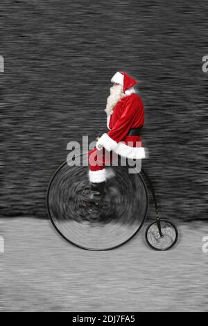 Padre Natale a cavallo di una bicicletta Penny Farthing Foto Stock