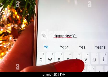 la mano femminile sta digitando sullo schermo di un bianco Smartphone il messaggio Happy New Ye Foto Stock
