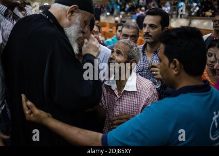 NO WEB/NO APPS - Padre Samaan Ibrahim, sacerdote copto, esegue una sessione di esorcismo presso la Chiesa di San Samaan (Simon), nota anche come Chiesa della Grotta nel villaggio di Mokattam, soprannominata "città della spazzatura", al Cairo, in Egitto, il 19 agosto 2016. Una volta alla settimana centinaia di musulmani si riuniscono nella chiesa dopo la preghiera, per assistere ad una sessione di esorcismo eseguita dal sacerdote. Con una croce e acqua Santa combatte entità spirituali e demoni. Il monastero ha un anfiteatro con una capacità di 20,000 posti a sedere che lo rende la più grande chiesa cristiana in Medio Oriente. Prende il nome dal santo copto, SIM Foto Stock