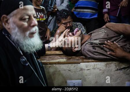 NO WEB/NO APPS - Padre Samaan Ibrahim, sacerdote copto, esegue una sessione di esorcismo presso la Chiesa di San Samaan (Simon), nota anche come Chiesa della Grotta nel villaggio di Mokattam, soprannominata "città della spazzatura", al Cairo, in Egitto, il 19 agosto 2016. Una volta alla settimana centinaia di musulmani si riuniscono nella chiesa dopo la preghiera, per assistere ad una sessione di esorcismo eseguita dal sacerdote. Con una croce e acqua Santa combatte entità spirituali e demoni. Il monastero ha un anfiteatro con una capacità di 20,000 posti a sedere che lo rende la più grande chiesa cristiana in Medio Oriente. Prende il nome dal santo copto, SIM Foto Stock