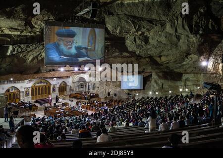 NO WEB/NO APPS - i fedeli frequentano un servizio come sacerdote copto Padre Samaan Ibrahim legge il suo sermone alla Chiesa di San Samaan (Simon), conosciuta anche come la Chiesa della Grotta nel villaggio di Mokattam, soprannominata "città della spazzatura", al Cairo, in Egitto, il 19 agosto 2016. Una volta alla settimana centinaia di musulmani si riuniscono nella chiesa dopo la preghiera, per assistere ad una sessione di esorcismo eseguita dal sacerdote. Con una croce e acqua Santa combatte entità spirituali e demoni. Il monastero ha un anfiteatro con una capacità di 20,000 posti a sedere che lo rende la più grande chiesa cristiana in Medio Oriente. Il nome deriva da t Foto Stock