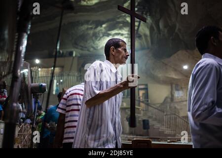 NO WEB/NO APPS - Padre Samaan Ibrahim, sacerdote copto, esegue una sessione di esorcismo presso la Chiesa di San Samaan (Simon), nota anche come Chiesa della Grotta nel villaggio di Mokattam, soprannominata "città della spazzatura", al Cairo, in Egitto, il 19 agosto 2016. Una volta alla settimana centinaia di musulmani si riuniscono nella chiesa dopo la preghiera, per assistere ad una sessione di esorcismo eseguita dal sacerdote. Con una croce e acqua Santa combatte entità spirituali e demoni. Il monastero ha un anfiteatro con una capacità di 20,000 posti a sedere che lo rende la più grande chiesa cristiana in Medio Oriente. Prende il nome dal santo copto, SIM Foto Stock