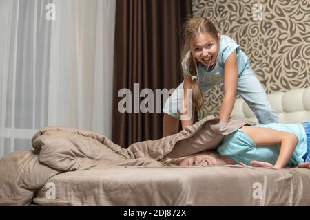 Due sorelle si divertono sul letto e combattono i cuscini. Alta qualità Foto Stock