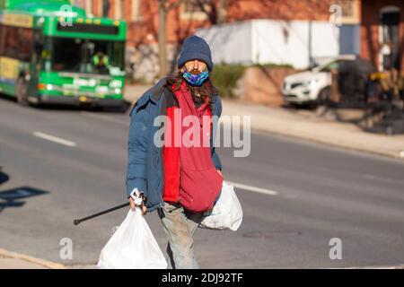 Frederick, Maryland, USA 11-22-2020: Un uomo senza casa caucasico dai capelli lunghi sta camminando nella strada nel centro di Frederick indossando sporco vecchio coagulo invernale Foto Stock