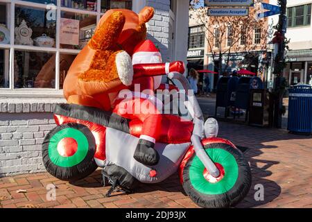 Alexandria, VA, USA 11-28-2020: Un arredamento di Natale creativo di fronte a un negozio di articoli da regalo con un grande giocattolo gonfiabile Babbo Natale che corre su una moto w Foto Stock