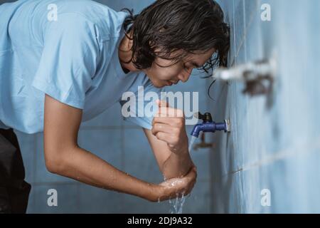 L'uomo musulmano esegue l'abluzione (wudhu) lavando la mano prima della preghiera. Foto Stock