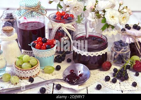 Produzione marmellata di frutta concetto. Bacca fresca su tavola di legno, estate natura morta e cibo rustico vintage sfondo. Frutta conservata Foto Stock