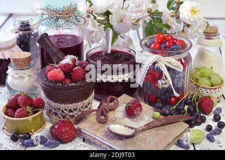 Produzione marmellata di frutta concetto. Bacca fresca su tavola di legno, estate natura morta e cibo rustico vintage sfondo. Frutta conservata Foto Stock