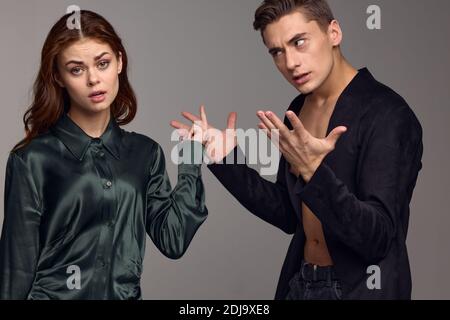 Uomo indignato e donna emozionale su sfondo grigio Foto Stock