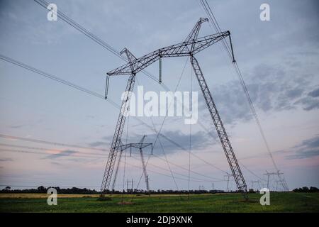 Grandi supporti metallici di linee elettriche che attraversano campi agrari. Linee ad alta tensione. Foto Stock