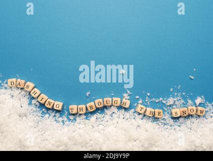 Piccoli blocchi di legno con l'iscrizione che scita attraverso la neve e fiocchi di neve su sfondo blu, spazio per il testo Foto Stock