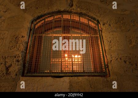 Una menorah è illuminata all'interno di una finestra, in un'antica casa nel quartiere ebraico della città vecchia di Gerusalemme Foto Stock